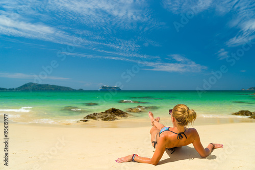 Young woman in bikini laying by the tropical sea