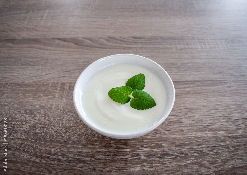 Ceramic bowl of white yogurt with mint leaves as decoration isolated on vintage rustic wooden table from top view, plain yoghurt Ceramic bowl of white yogurt with mint leaves as decoration isolated on vintage rustic wooden table from top view, plain yoghurt
