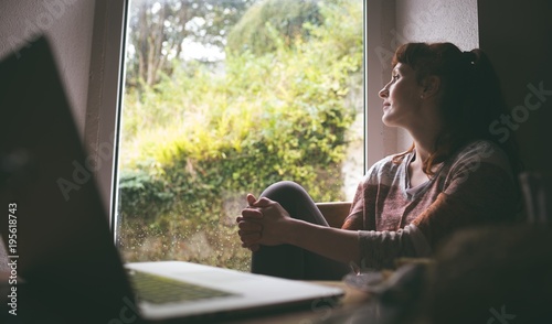 Thoughtful woman sitting near window photo