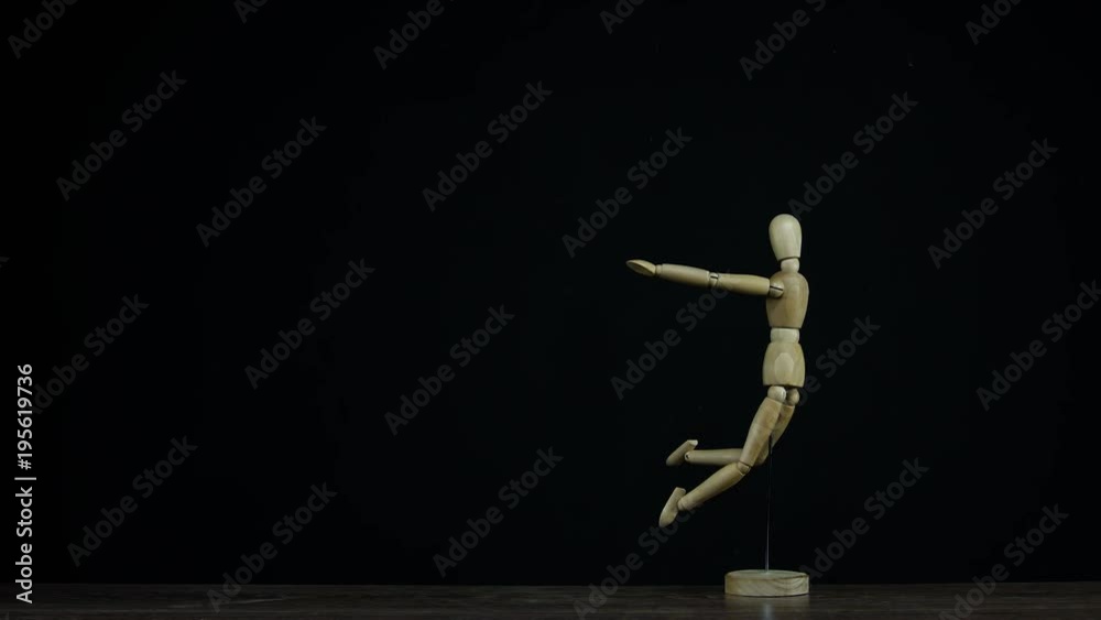 Stopmotion falling wooden figure dummy in studio on black background rotating for titles Stopmotion falling wooden figure dummy in studio on black background rotating for titles