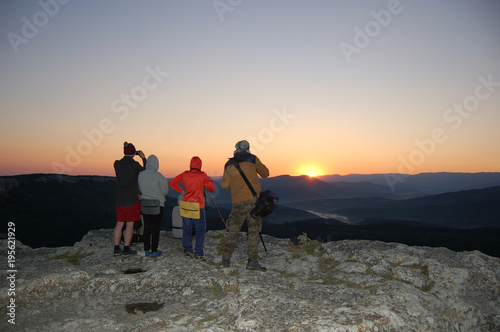 tourists watch the sun rise on the mountain