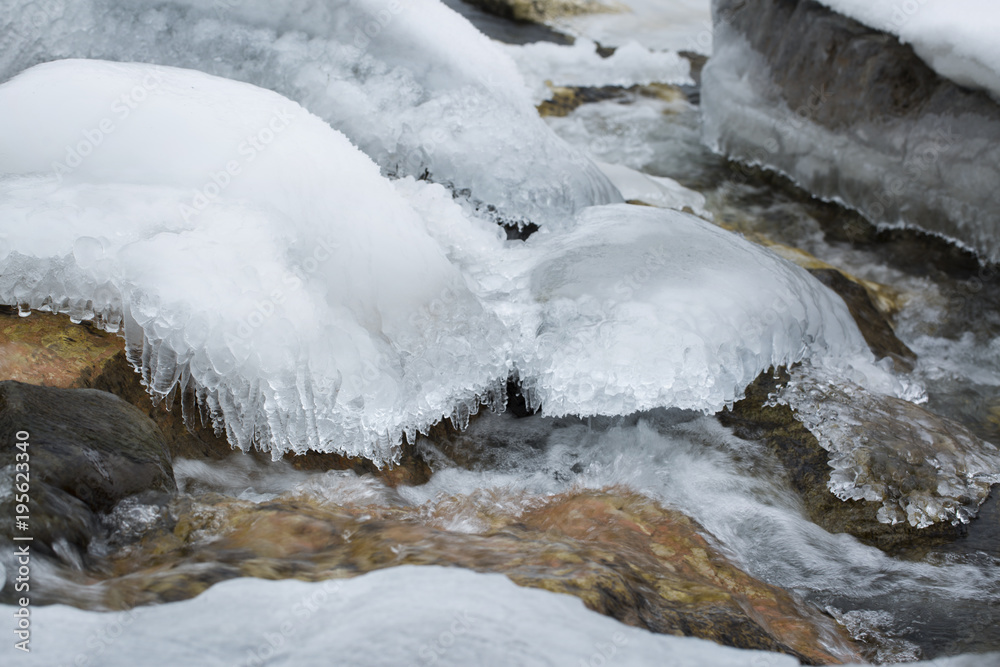 Frozen alpine river in winter in slow motion. Stones covered with frost and snow. Frozen alpine river in winter in slow motion. Stones covered with frost and snow.