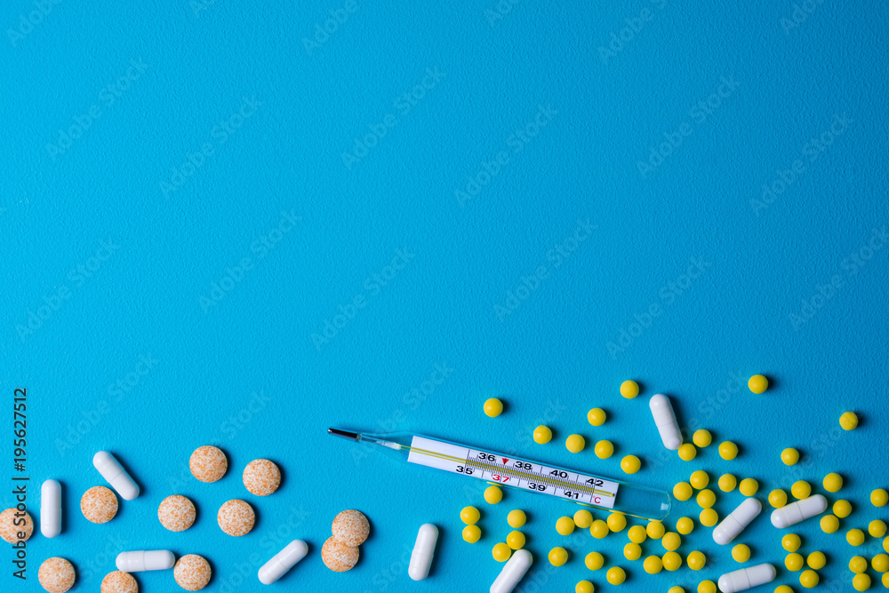 Medical background. Thermometer, pills on a blue background. Medicine, health care, flu treatments concept. Copy space, top view Medical background. Thermometer, pills on a blue background. Medicine, health care, flu treatments concept. Copy space, top view