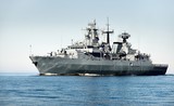 Grey modern warship sailing in still water