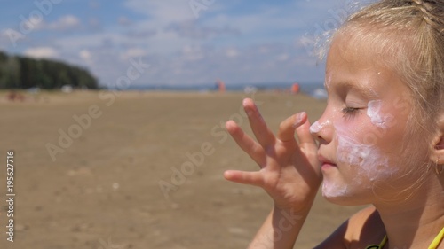 The girl apply sunscreen to face and body. The girl squeezes the sunscreen into her palm and puts it on her face.