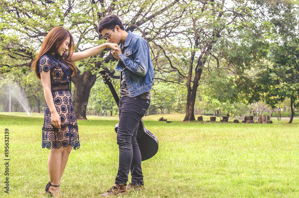 beautiful young couple standing kiss on the park with a guitar. beautiful young couple standing kiss on the park with a guitar.