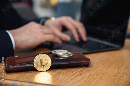 Businessman works on a laptop in his workplace. Cryptocurrency business concept. Electronic virtual money investment. Gold bitcoin coin, Litecoin, Ethereum coins on the wallet. Selective focus.