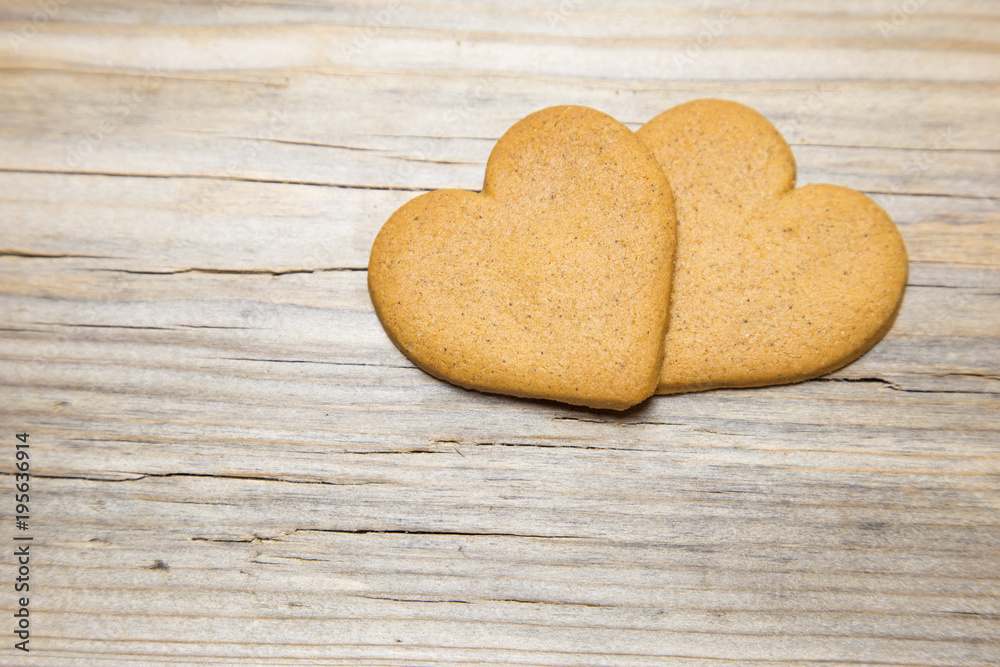 Obraz premium Two heart shaped gingerbread cookies on wooden background.