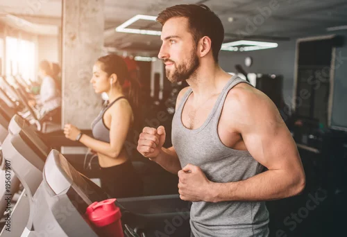 Obraz Zamknij się z dwóch dobrze zbudowanych osób, które działają na uruchomionej maszynie. Bardzo ciężko ćwiczą. Wytnij widok.