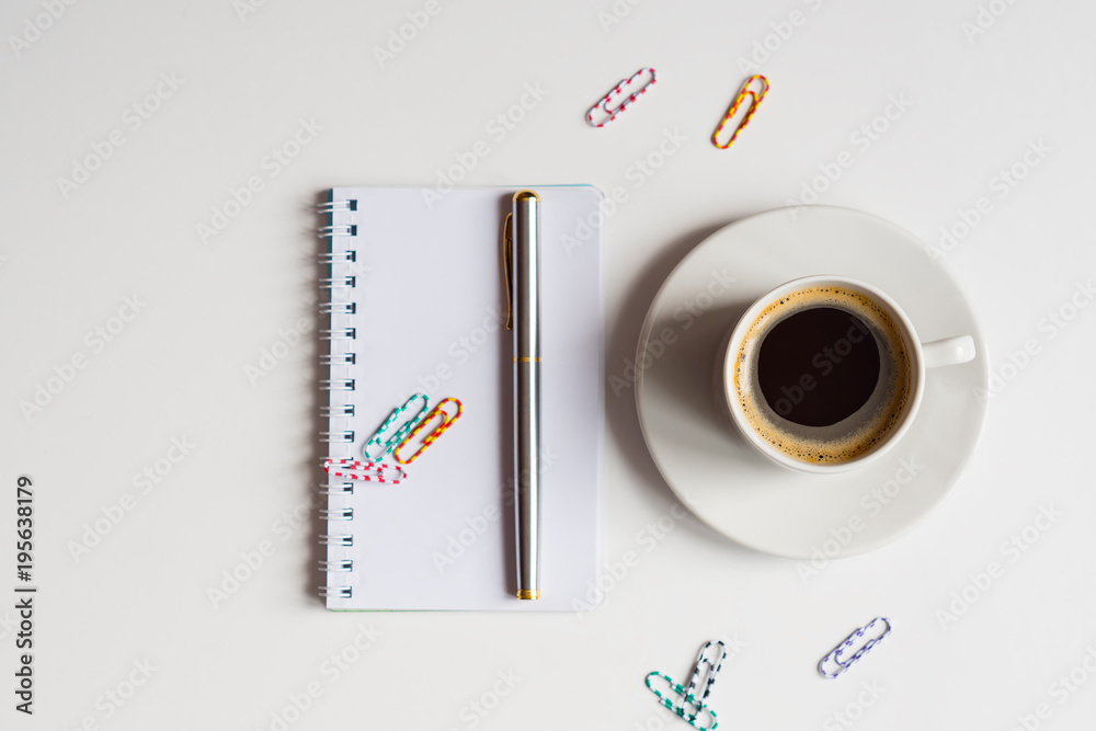 cup of black coffee with notebook, clips and pen on white background. business concept with copy space cup of black coffee with notebook, clips and pen on white background. business concept with copy space