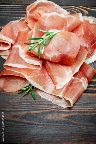 Italian prosciutto crudo or spanish jamon. Raw ham on wooden background