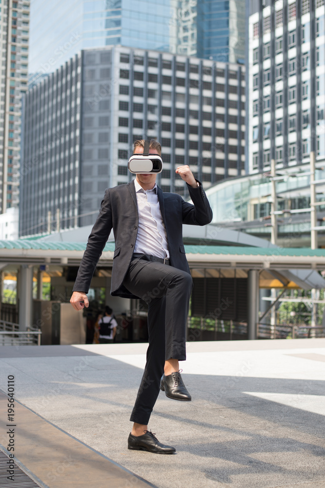 Caucasian Businessman wear black suit and Virtual Reality Headset (VR) and fighting by kick to the air Caucasian Businessman wear black suit and Virtual Reality Headset (VR) and fighting by kick to the air
