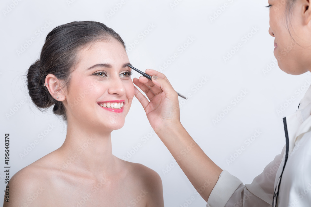 Young beautiful woman applying make-up by make-up artist isolated on white. Young beautiful woman applying make-up by make-up artist isolated on white.