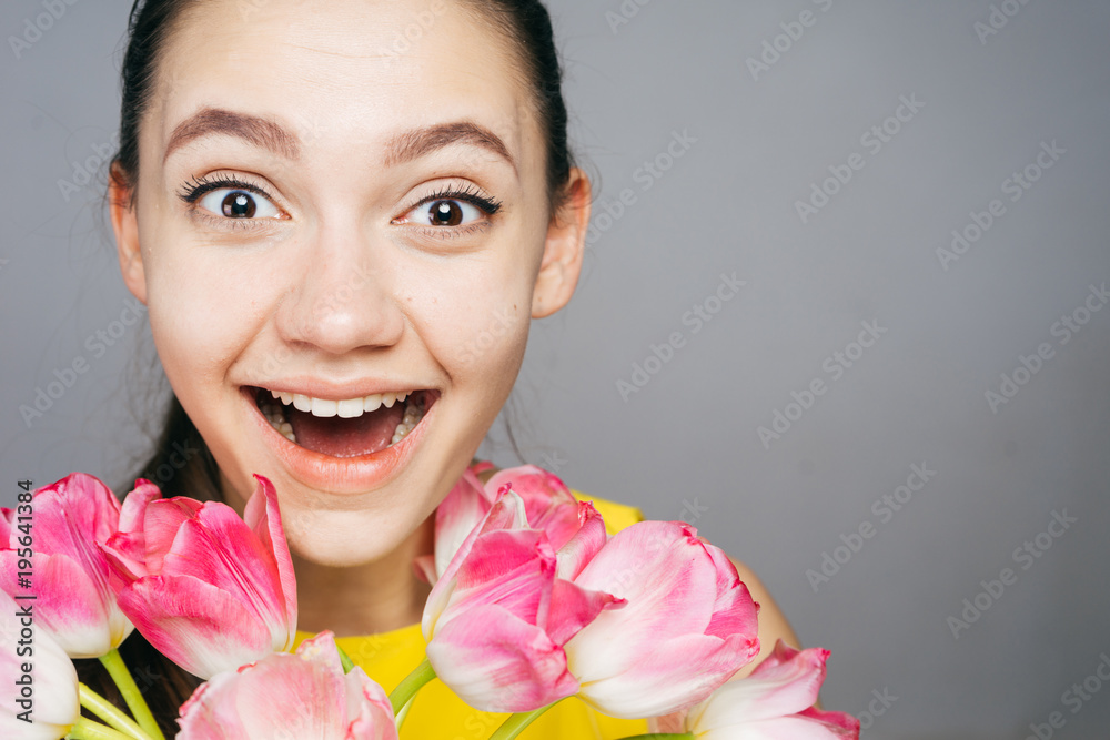the amazed woman holding a bouquet of flowers in her hands, on March 8 the amazed woman holding a bouquet of flowers in her hands, on March 8