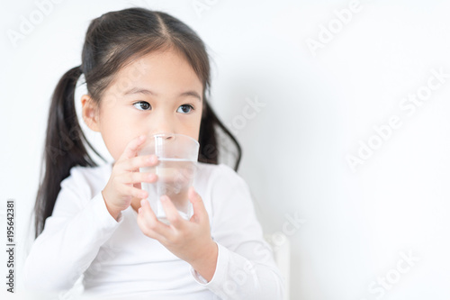 Pretty girl is drinking a glass of water and looking at outside.