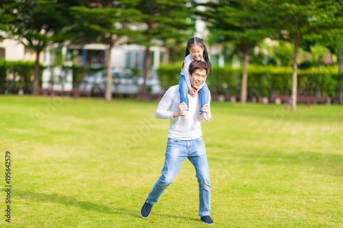 Cute Asian girl on neck dad big happy laughing and run around together.Happy man piggybacking adorable little kid is smiling.