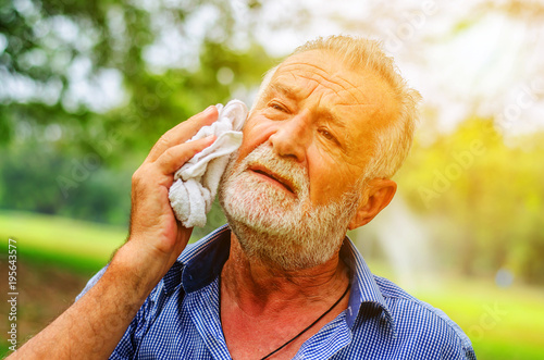 Senior man wiping sweat of his with towel in park