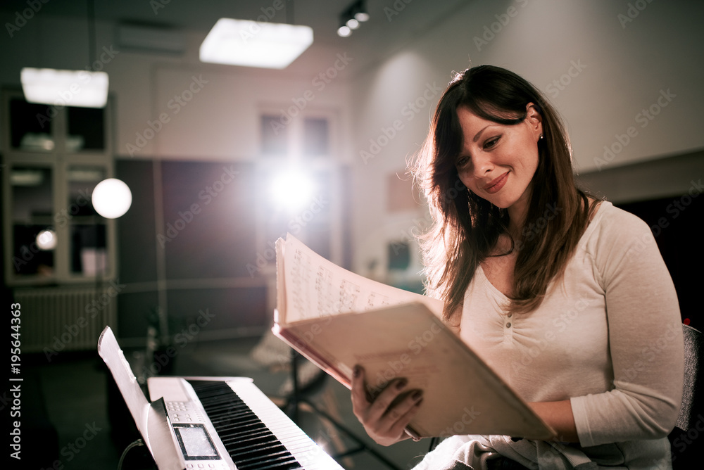Obraz premium Smiling woman reading music sheet.