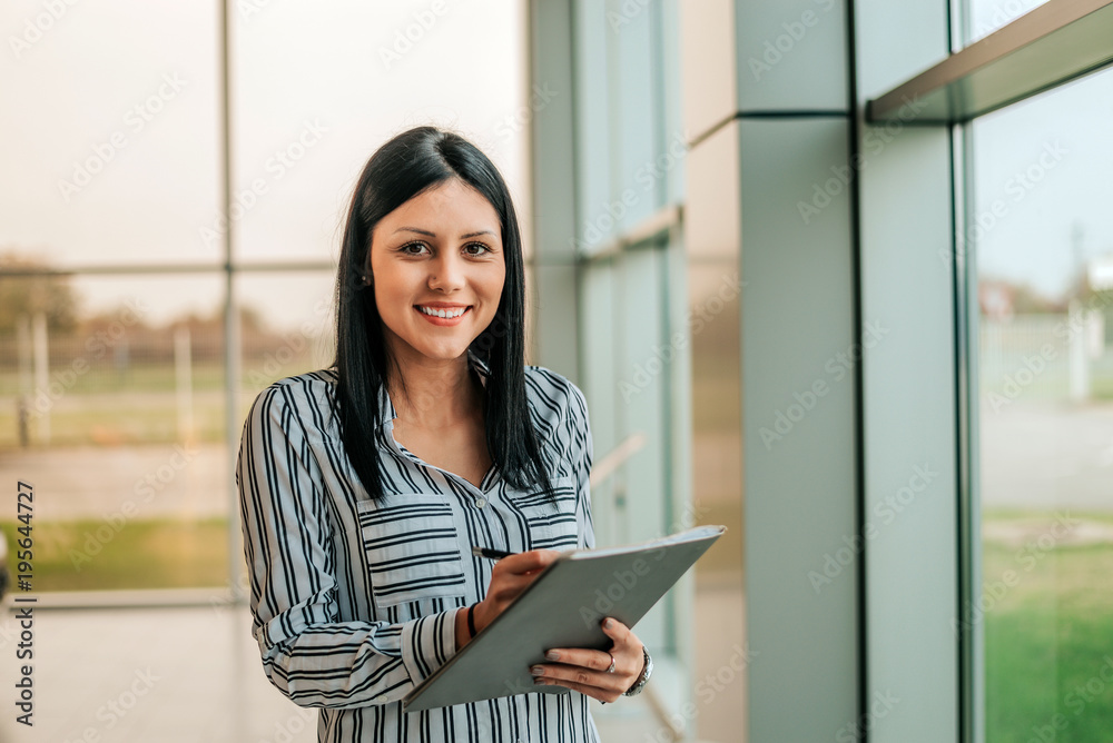 Smiling car saleswoman woman holding documents. Looking at camera. Smiling car saleswoman woman holding documents. Looking at camera.