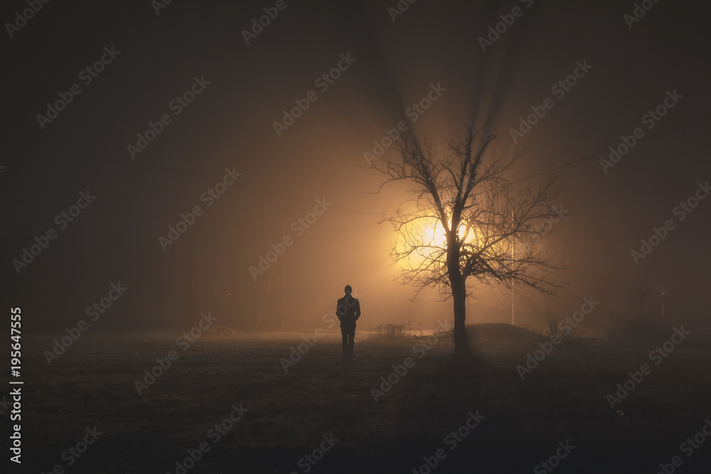 Man alone standing on a foggy night