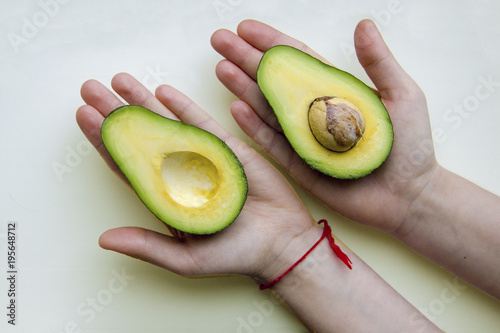 Two halves of avocado on children's palms