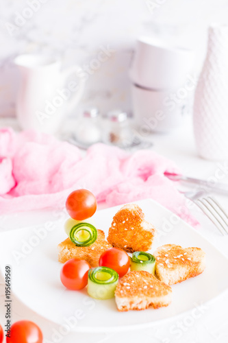Toasts in the form of heart, cherry and cucumber on a plate. Dish served for lovers.
