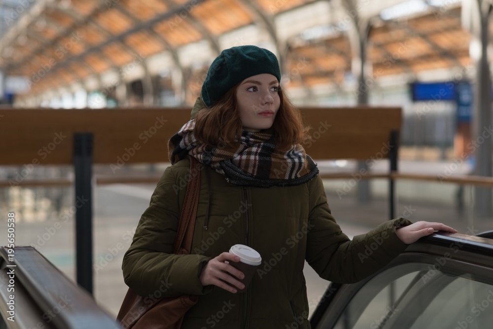 Woman holding coffee cup on escalator Woman holding coffee cup on escalator