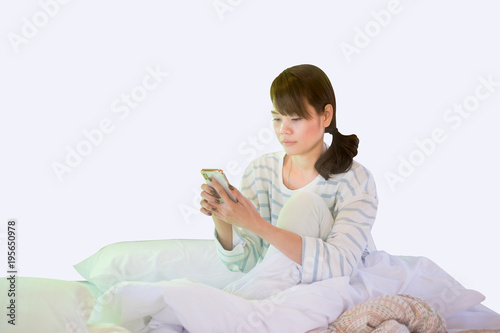 Asian women playing mobile phones On Her White Bed While Waking Up.Isoleted Dicut Clipping Path Image.
