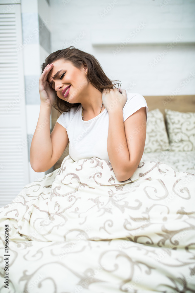 Young Woman Suffering From Neck Pain Sitting On Bed at home Young Woman Suffering From Neck Pain Sitting On Bed at home