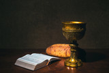 Goblet with wine bread and Holy Bible on a table