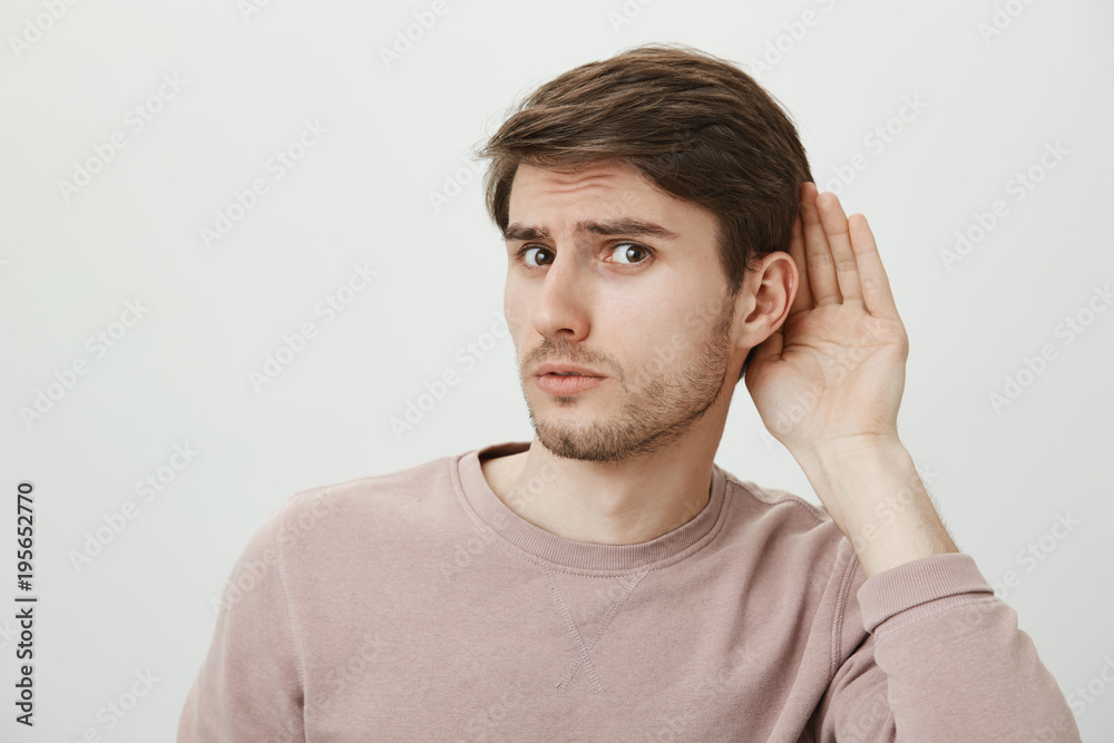 Boyfriend do not believe his couple and spying on her. Portrait of worried guy having trust issues, frowning and looking anxious while eavesdropping conversation of girlfriend, standing over gray wall Boyfriend do not believe his couple and spying on her. Portrait of worried guy having trust issues, frowning and looking anxious while eavesdropping conversation of girlfriend, standing over gray wall