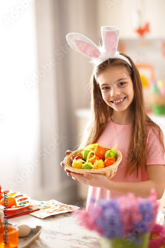 Child hold basket with colorful easter eggs.