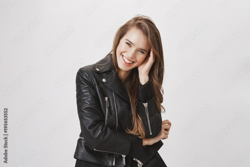 Hearing out great stories from friend. Portrait of emotive charming modern woman tilting head, holding hand on face, laughing while talking with boyfriend, having date in park, wearing leather jacket Hearing out great stories from friend. Portrait of emotive charming modern woman tilting head, holding hand on face, laughing while talking with boyfriend, having date in park, wearing leather jacket