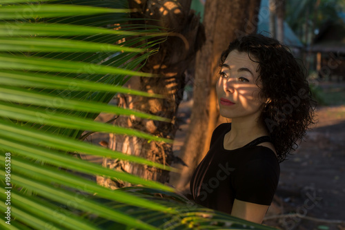 Beautiful asian girl looks through the palm leaves.. photo