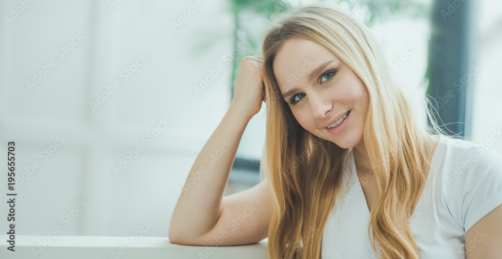 Close up Portrait of a beautiful smiling young blond woman sitting at home on a sofa and resting or relaxing. Close up Portrait of a beautiful smiling young blond woman sitting at home on a sofa and resting or relaxing.