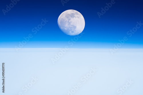 Moon rising from the Earth horizon above the clouds. 