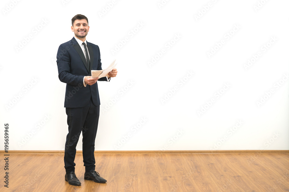 The happy businessman holding papers on the white wall background The happy businessman holding papers on the white wall background