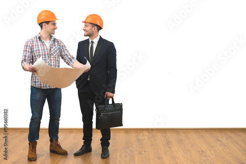 The engineer and a businessman stand with a paper on the white wall background
