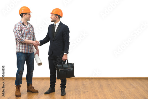 The engineer and a businessman handshake on the white wall background