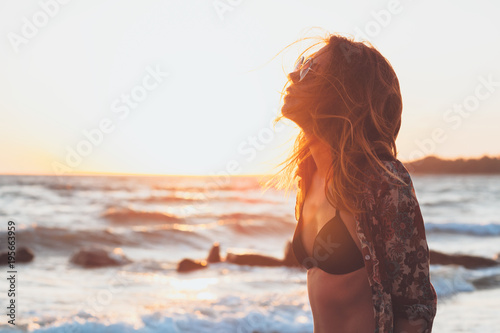 Young woman enjoying sunset and waves at the beach