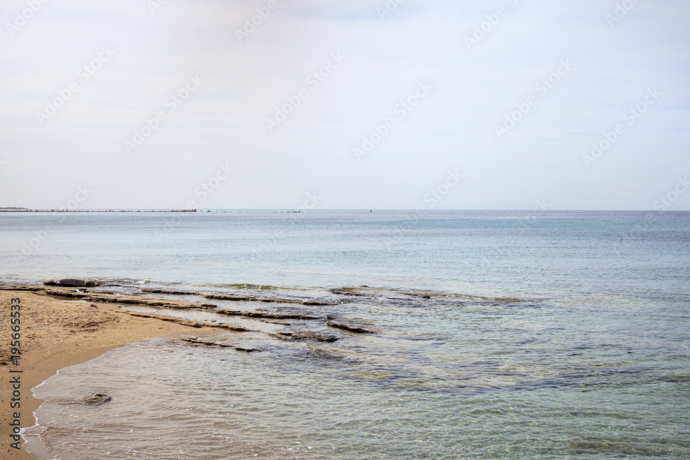 Sandy beach with rocks. Blue sky and sea background.