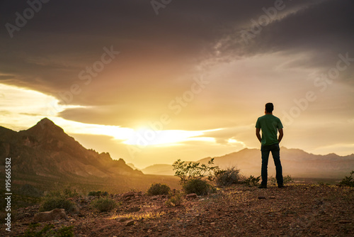 Canvas Print man watching golden sunset over mountains in nevada desert