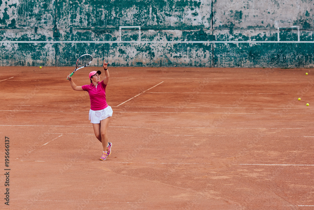 Tennis player. Active sportive woman playing tennis, ready for receive a ball, dressed in pink t-shirt, cap and white skirt. Side view from tribune.