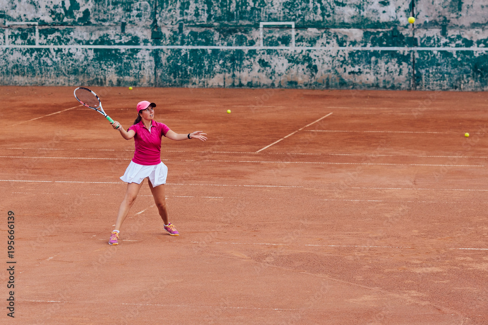 Tennis player. Active sportive woman playing tennis, ready for receive a ball, dressed in pink t-shirt, cap and white skirt. Side view.