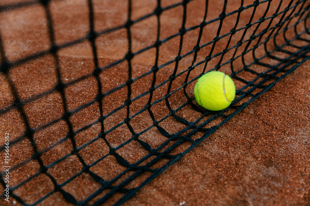 Close-up view of tennis ball caught in the net. Outdoors.
