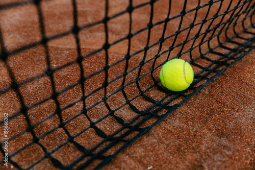 Close-up view of tennis ball caught in the net. Outdoors. © Maksym Azovtsev