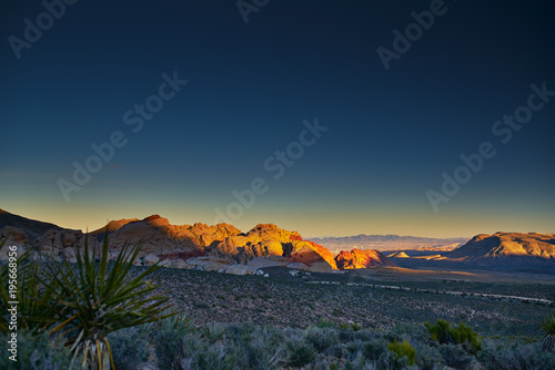 sun setting over redrock canyon rocks with las vegas in background