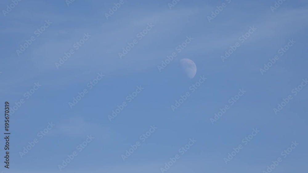 Zoom out from a half moon in a bright blue sky to reveal several wind turbines. Zoom out from a half moon in a bright blue sky to reveal several wind turbines.
