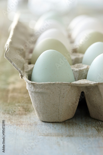 Close-up of Dozen Blue, Green and White Eggs in Cardboard Egg Carton on Wooden Tabletop