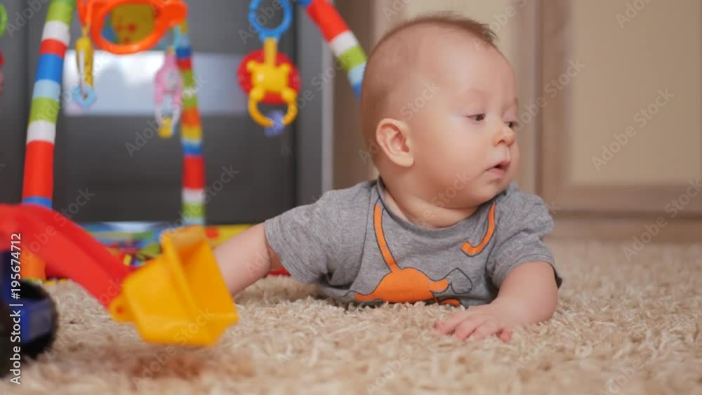 Baby boy lying on the floor playing with an excavator. The concept of children's toys. Baby boy lying on the floor playing with an excavator. The concept of children's toys.